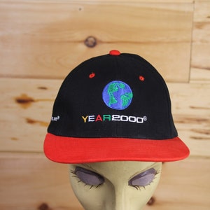 Könnte beinhalten: Schwarze und rote Baseballkappe mit einem gestickten blauen und grünen Globus und dem Text "YEAR 2000".