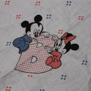 May include: A white fabric with red and blue polka dots. Mickey Mouse and Minnie Mouse are holding a red and white polka dot letter B. The text "The Walt Disney Co." is in the bottom left corner.