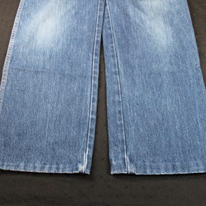 May include: A pair of blue denim jeans with a straight leg fit. The jeans have a light wash and a faded appearance.