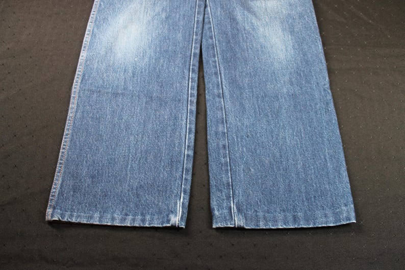 May include: A pair of blue denim jeans with a straight leg fit. The jeans have a light wash and a faded appearance.