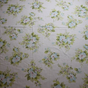 May include: White fabric with a repeating pattern of light blue flowers and green leaves.