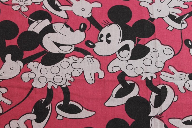 Peut inclure: Tissu rose avec un motif r&eacute;p&eacute;t&eacute; de Minnie Mouse en noir et blanc. Minnie porte une robe blanche &agrave; pois noirs. Le tissu convient &agrave; divers projets de couture.