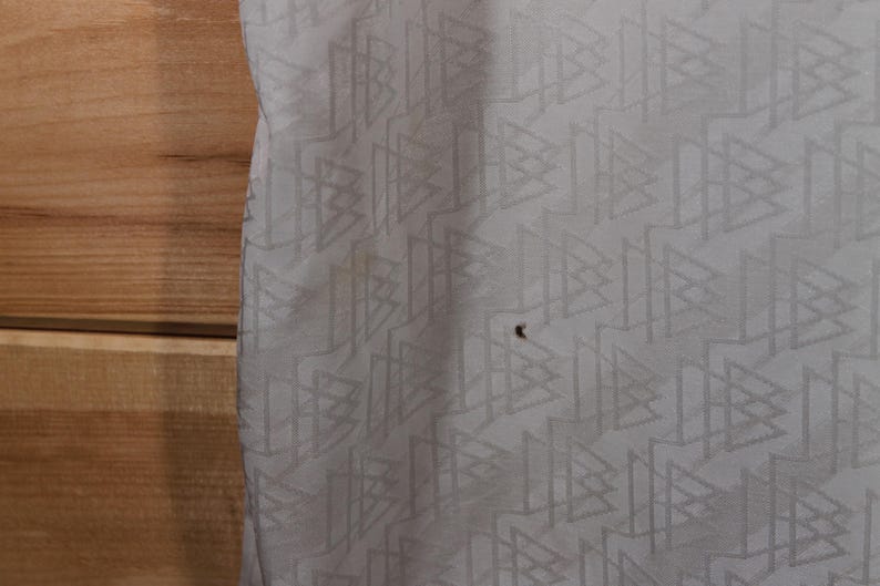 May include: White fabric with a repeating geometric pattern of triangles and lines.