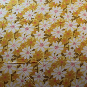 May include: A fabric featuring a repeating floral pattern. White daisies with pink centres and yellow-orange daisies are set against a yellow background. Brown stems and leaves complete the design, creating a cheerful, vintage aesthetic.