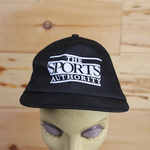 May include: Black baseball cap with a white logo that reads "THE SPORTS AUTHORITY".