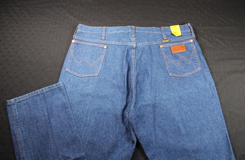 May include: A pair of blue denim jeans with a brown leather patch on the back pocket. The jeans have a classic straight leg style.