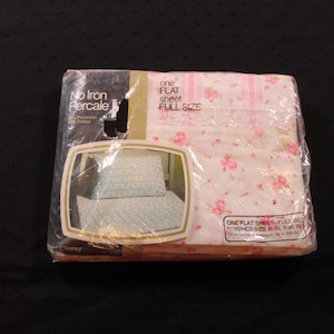May include: A packaged full-size flat sheet. The sheet is white with a pink floral pattern. The packaging reads "No Iron Percale" and "One Flat Sheet Full Size". The finished size is 206 x 264 cm.