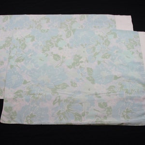 May include: Two white pillowcases with a light blue and green floral pattern.