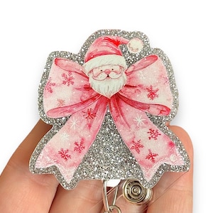 May include: A silver glitter Christmas themed badge reel with a pink bow and a Santa Claus face in the center.