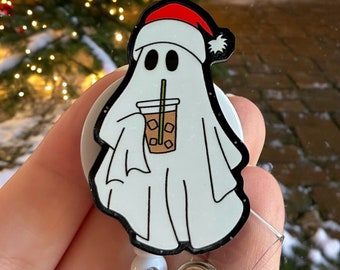 May include: A white ghost wearing a red Santa hat and holding a cup of iced coffee. The ghost is attached to a retractable badge reel with a clear plastic badge holder.