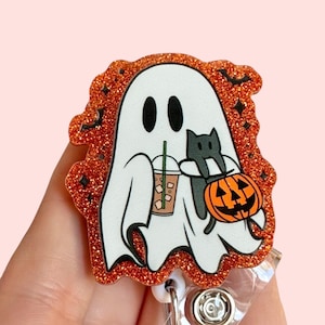 May include: Orange glitter Halloween-themed retractable badge holder with a white ghost holding a pumpkin and a black cat. The ghost is holding a cup of coffee.