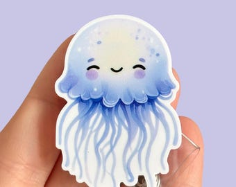 Könnte beinhalten: Eine blaue und weiße Cartoon-Qualle mit einem lächelnden Gesicht. Die Qualle befindet sich auf einem durchsichtigen Plastik-Badge-Halter.