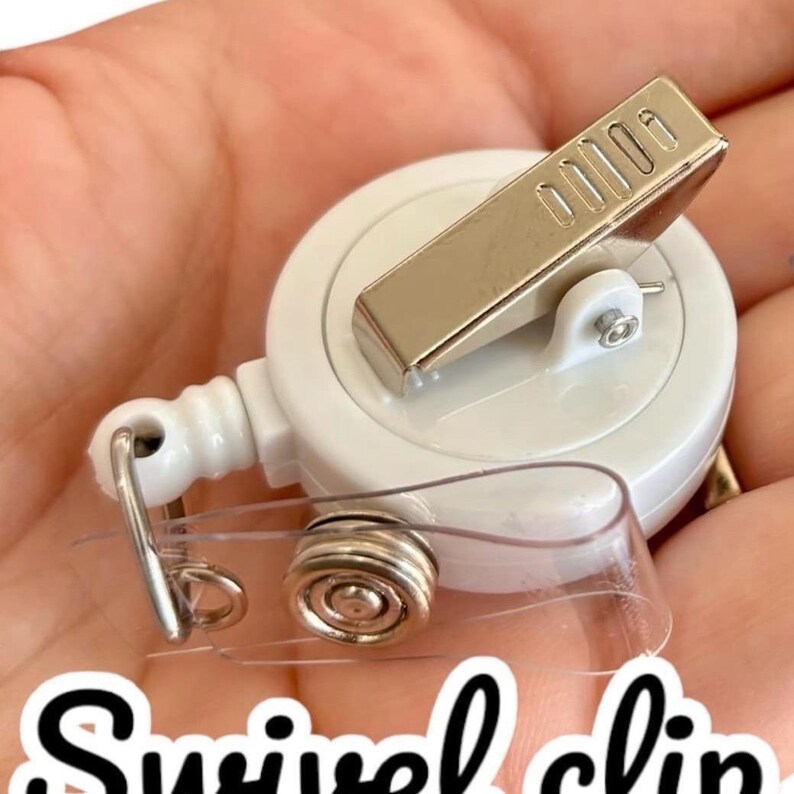 Puede incluir: Un carrete de insignia con clip giratorio blanco con un clip de metal plateado y una correa de pl&aacute;stico transparente. El texto "Swivel clip" est&aacute; escrito en fuente cursiva negra en la parte inferior de la imagen.