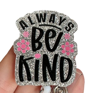 May include: Silver glitter badge holder with a black and pink design that says "Always Be Kind" with pink flowers.
