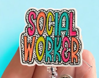May include: A white badge holder with a colorful "SOCIAL WORKER" design. The letters are outlined in black and have a polka dot pattern. The badge holder has a clear retractable cord.