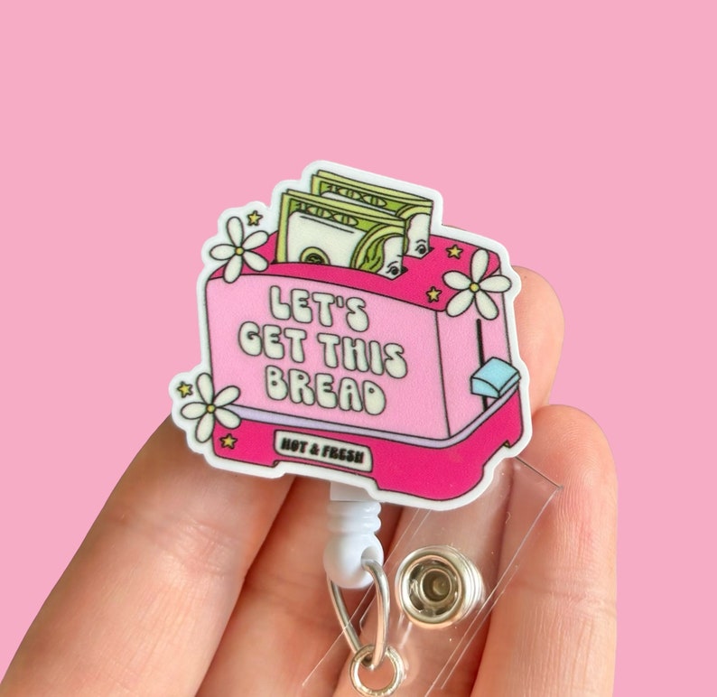 May include: Pink plastic badge holder with a cartoon image of a toaster with money inside. The toaster has the text "Let's Get This Bread" and "Hot & Fresh" printed on it.