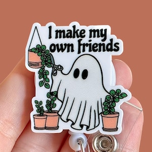 May include: A white ghost with black eyes holding a potted plant. The text "I make my own friends" is above the ghost. The image is a badge reel.