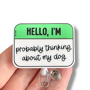 May include: White badge holder with a green background and the text "HELLO, I'M probably thinking about my dog".