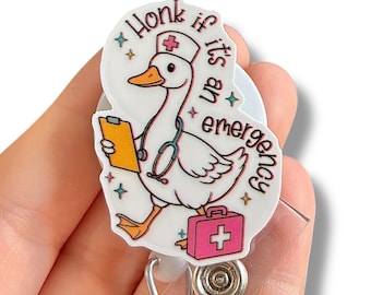 May include: A white and pink badge reel featuring a cartoon goose wearing a nurse's hat and holding a clipboard and medical bag. The text reads "Honk if it's an emergency". The badge reel has a silver clip and retractable cord.