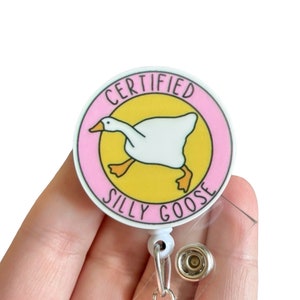 May include: A pink and yellow round badge with a white goose illustration and the text "CERTIFIED SILLY GOOSE".