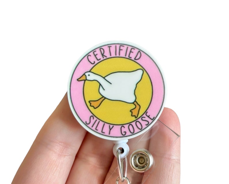May include: A pink and yellow round badge with a white goose illustration and the text "CERTIFIED SILLY GOOSE".