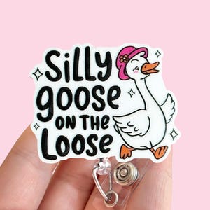 May include: White badge holder with a cartoon goose wearing a pink hat and the text "Silly goose on the loose".