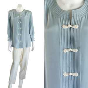 Long blue silk blouse with white pants. The top has shoulder pads and white frog closures