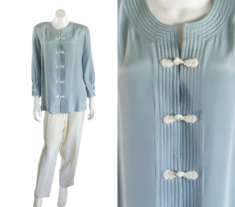 Long blue silk blouse with white pants. The top has shoulder pads and white frog closures