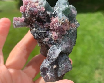 May include: A cluster of green and pink crystals with a rough, natural texture. The crystals are arranged in a random, organic pattern.