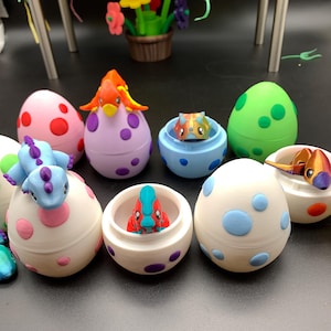 May include: A collection of colorful, decorative egg-shaped containers, each with a unique design and a small dinosaur figurine inside. The eggs are various colors, including pink, green, and white, with contrasting polka dots. Some eggs are open, revealing the dinosaur toys.