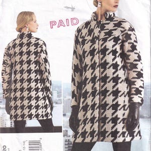 May include: A black and white houndstooth pattern coat with a high collar and button closure. The coat is shown on a model wearing black gloves. The pattern is labelled "V1320" and "ISSEY MIYAKE" with the text "PAID" in red.