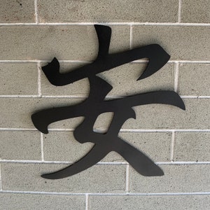May include: Black metal wall art featuring the Chinese character for "family" in a stylized design. The character is mounted on a gray brick wall.