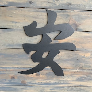 May include: Black metal wall art featuring the Japanese kanji character for "love".