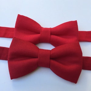 May include: Two red bow ties made of fabric. The bow ties are tied and ready to wear.