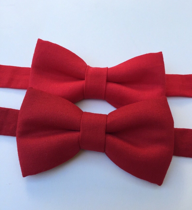 May include: Two red bow ties made of fabric. The bow ties are tied and ready to wear.