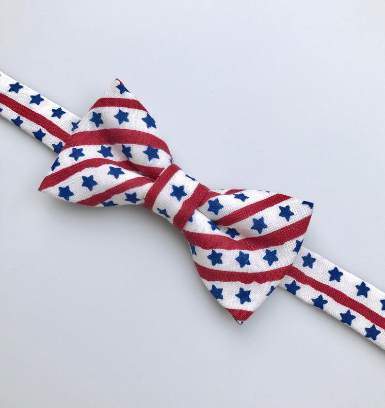 May include: A white bow tie with red and blue stripes and white stars.