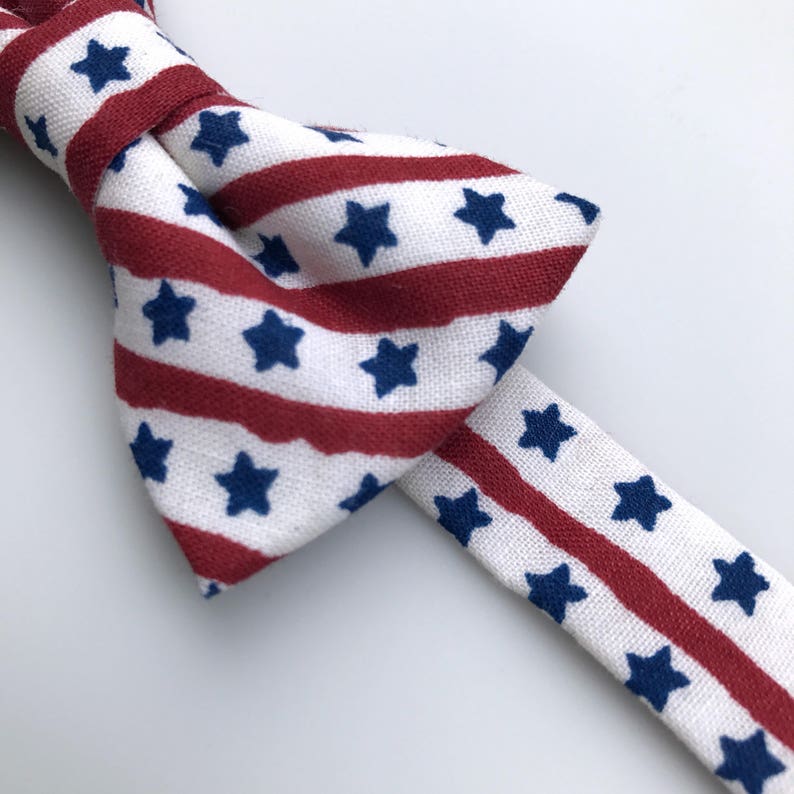 May include: A red, white, and blue bow tie with a striped pattern and white stars. The bow tie is made of fabric and is suitable for a special occasion.