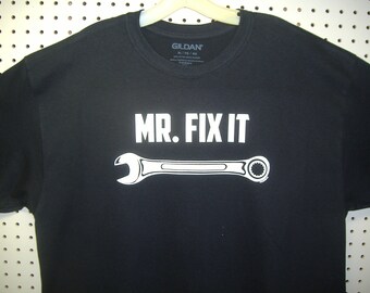 May include: Black t-shirt with white text that reads "MR. FIX IT" and a wrench graphic.
