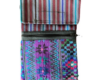 May include: A small, purple and blue patterned zippered pouch with a striped fabric flap. The pouch is made of woven fabric and has a zipper closure.