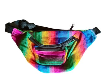 May include: A colourful rainbow striped fanny pack with a black zipper and a small zippered pocket on the front.