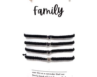 May include: Set of four black friendship bracelets with silver heart charms. The bracelets are strung on a clothesline with wooden clothespins. The text "Family" is written above the bracelets. The text below the bracelets reads "wear this as a reminder that our family bond will last forever, that no matter where we are in life, we are always there for each other. giftsandknots.etsy.com"