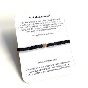 May include: A black string bracelet with a gold heart charm. The card attached to the bracelet reads "You are a runner. You have good runs and tough runs; on days and off days; weeks of incredible progress and weeks of falling behind schedule, but you will never have a bad run because there is no such thing. Every run is a blessing. Let me say that again. Every single run is a blessing and I am proud of every run you've done - fast, slow, long or unexpectedly short - simply because you did it."