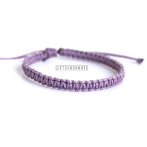 May include: A purple braided friendship bracelet with a simple knot design. The bracelet is made with a soft, durable cord and is adjustable to fit most wrists.