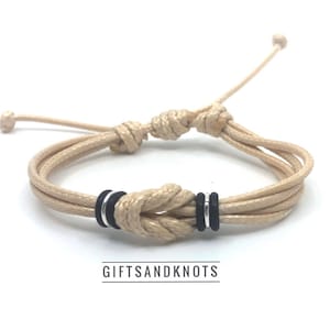 Nautical Knot Bracelet with black and silver accent rings. Adjustable beige cord design, Unisex gift for beach lovers or surfers.