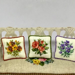 Cojín de casa de muñecas en miniatura, con pequeños bordados de flores de puntada sobre lienzo de lino.