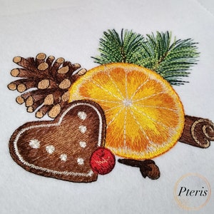 May include: Embroidered design featuring a gingerbread heart, an orange slice, a pine sprig, a cinnamon stick, and a clove. The design is in shades of brown, orange, yellow, green, and red.