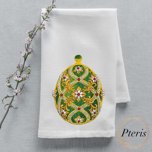 May include: A white kitchen towel with an embroidered green and gold Easter egg design. The egg is decorated with white flowers and red jewels.