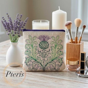 Peut inclure: Trousse de maquillage beige avec une fermeture éclair violette et un motif de chardon brodé en vert et violet. Le sac est sur une surface en bois, à côté de pinceaux de maquillage, d'une bougie et d'un vase de lavande. Le mot "Pteris" est dans l'image.