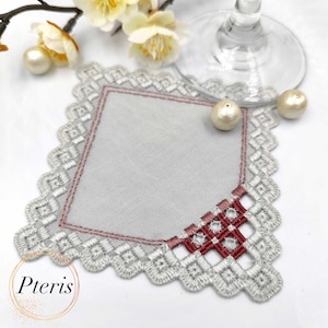 May include: Square, gray embroidered coaster with a scalloped edge and a red and gray geometric design. The coaster has a light gray center and the word "Pteris" in a gold circle.