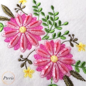 Puede incluir: Diseño bordado con dos flores rosas con centros amarillos y hojas verdes. Las flores están bordadas en 3D, lo que les da un aspecto en relieve.